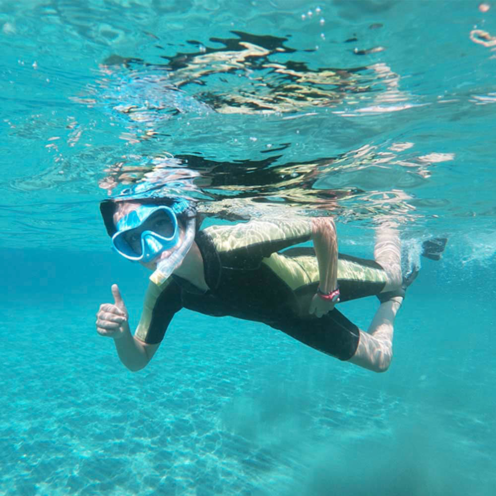 Niño buceando con gafas de bucear, tubo y neopreno bajo el mar de almeria